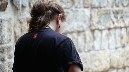 Rear view of woman standing against wall