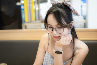 Close-up of young woman wearing eyeglasses looking down in restaurant