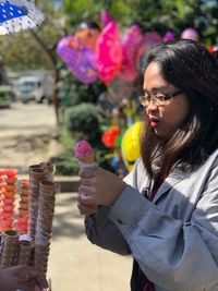 Young woman buying ice cream cone while standing on street