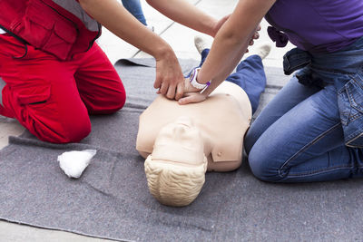 Midsection of people pressing figurine chest outdoors