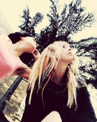 Beautiful young woman against trees against sky