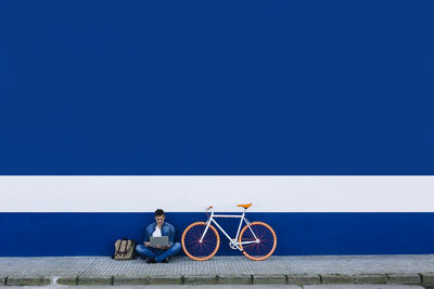 Man riding bicycle on road against clear blue sky