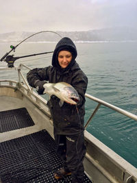 Woman holding fish in boat