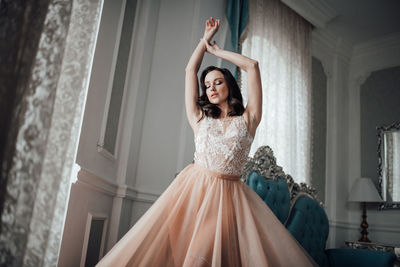 Woman wearing bridal dress standing at home