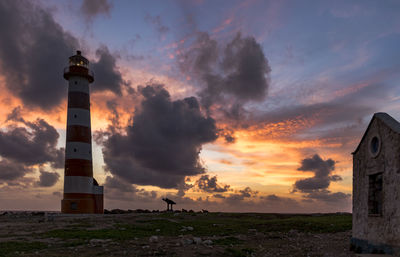 Lighthouse by sea against sky during sunset