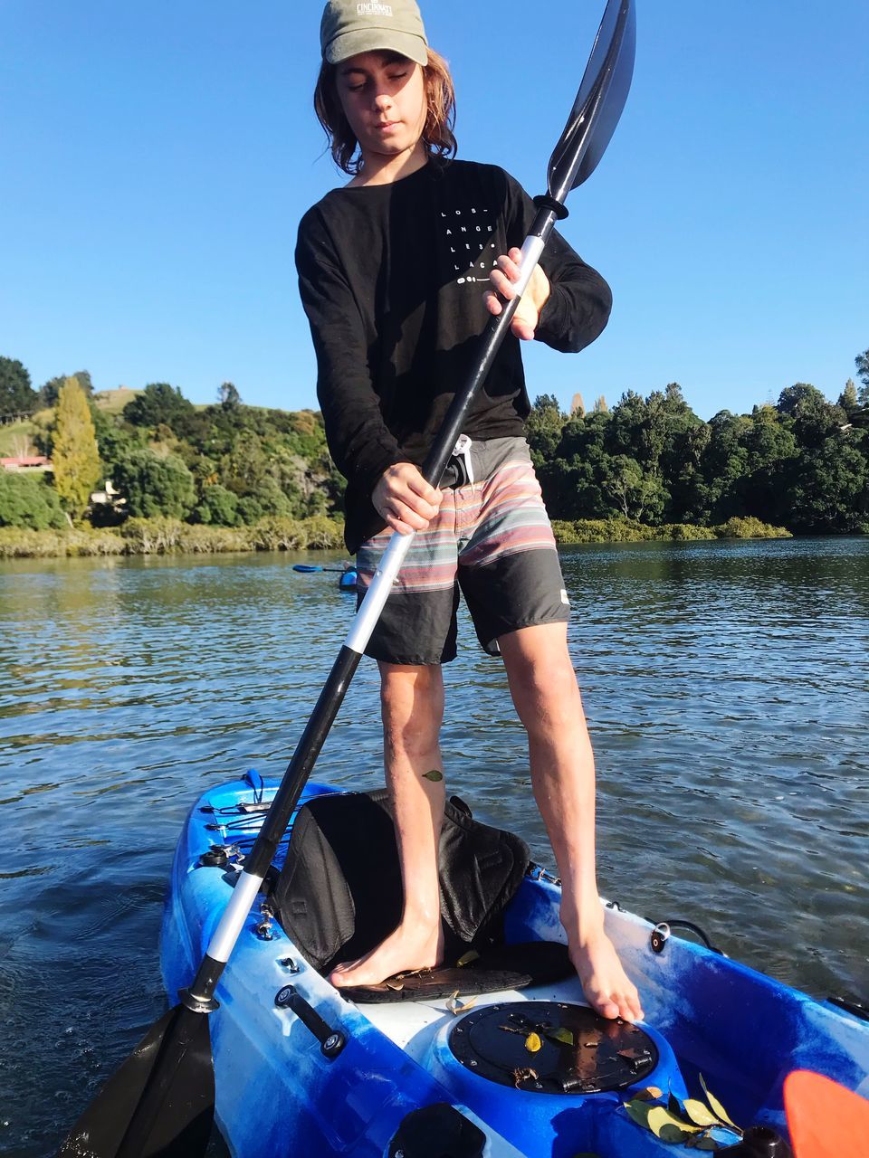 water, one person, real people, leisure activity, nautical vessel, oar, nature, lake, transportation, sky, mode of transportation, standing, day, casual clothing, lifestyles, adventure, front view, outdoors