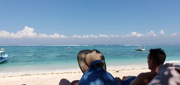 Rear view of people on beach against sky