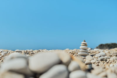 Pyramid stones balance on the beach against a blue bright sky. 