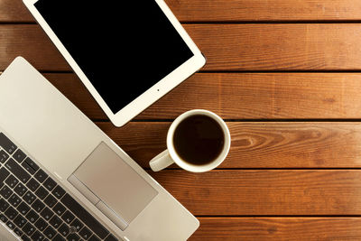 Directly above shot of laptop with coffee cup on table