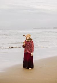 Woman standing at beach against sky