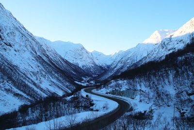 Scenic view of snow covered mountains against clear blue sky