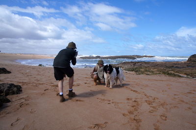 Rear view of couple with dog at beach
