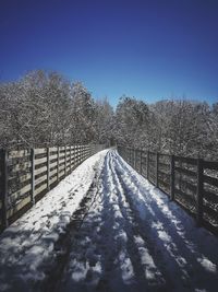 Snow covered footbridge against clear blue sky