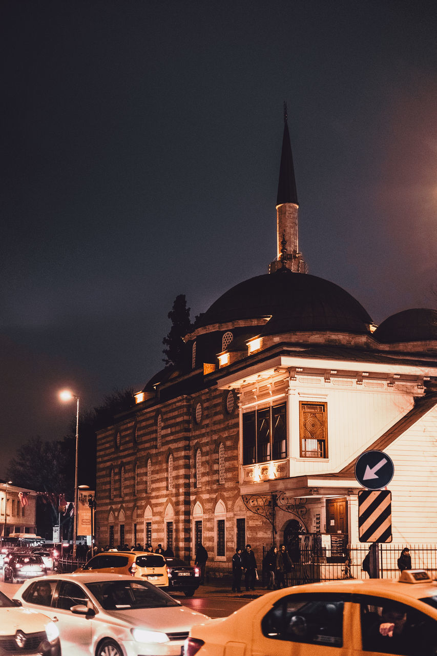 CARS IN ILLUMINATED CITY AT NIGHT