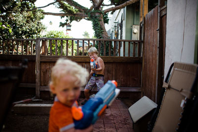 Brothers playing with water guns in front yard