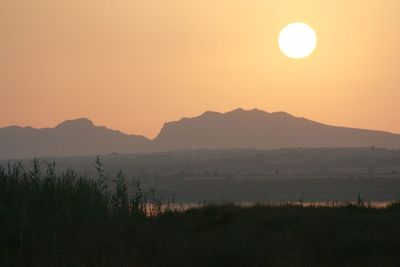 Grass with lake and silhouetted mountains a dusk