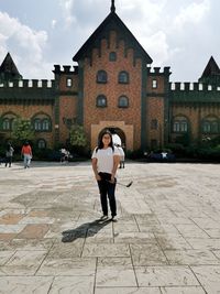 Full length of woman standing by building in city