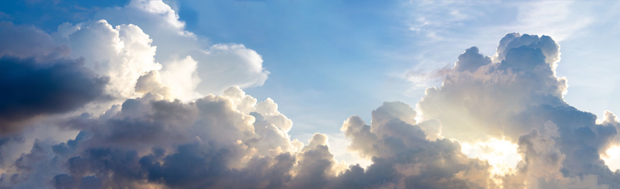 LOW ANGLE VIEW OF SUN STREAMING THROUGH CLOUDS DURING SUNSET