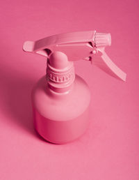 Close-up of pink spray bottle against colored background