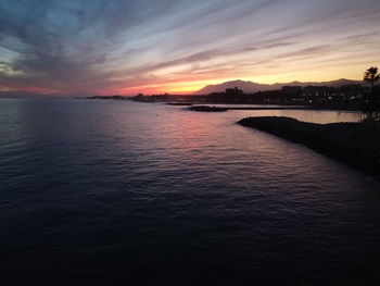 Scenic view of sea against dramatic sky during sunset