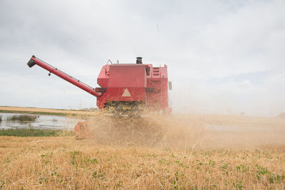 Machinery harvesting on field against sky