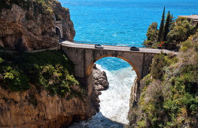 Arch bridge over sea by rocks