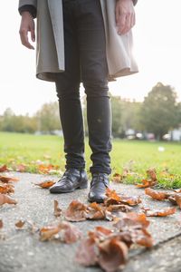 Low section of man standing on autumn leaves