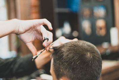 Cropped hands cutting customer hair