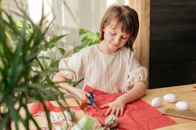 Making easter eggs in the shape of a hare from textile. the girl prepares the fabric, cuts it