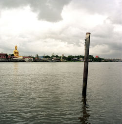 View of building by river against cloudy sky