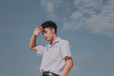 Low angle view of young man standing against sky