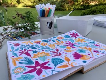 High angle view of a floral motif in an art journal, a sketchbook on a table in nature