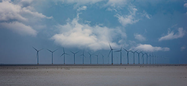 Modern windmill park in lake ijsselmeer in the netherlands. ragged clouds in the background.