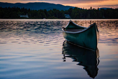 Boat moored on lake during sunset