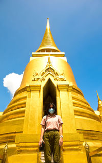 Low angle view of woman standing outside temple against building