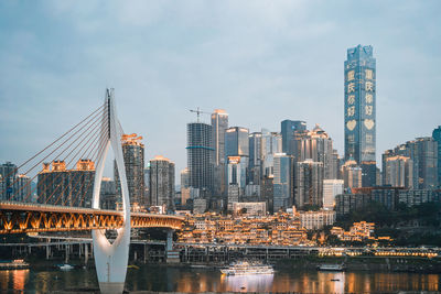 Bridge over river by buildings against sky in city