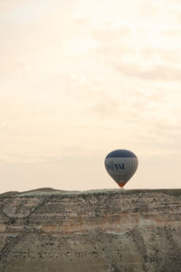 Hot air balloon flying over land against sky during sunset