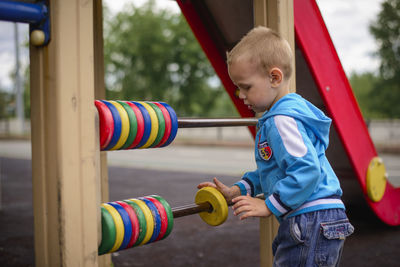 Side view of boy playing on slide at playground