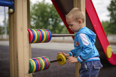 Side view of boy playing on slide at playground