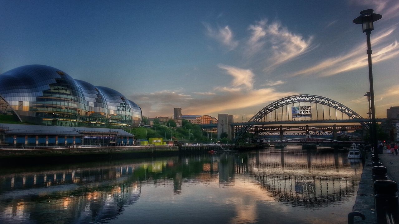 architecture, built structure, water, building exterior, sky, connection, river, bridge - man made structure, reflection, waterfront, city, transportation, cloud - sky, travel destinations, famous place, arch bridge, travel, illuminated, capital cities, arch