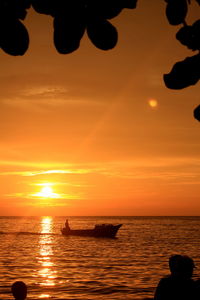 Silhouette people on sea against sky during sunset