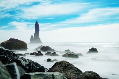 Scenic view of stack rock in sea against sky