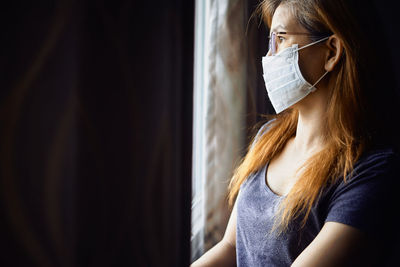 Woman in mask at the window during covid-19 pandemic