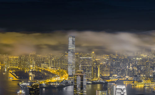 Illuminated modern buildings in city against sky at night