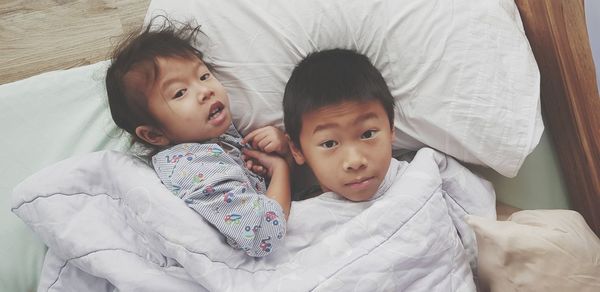 High angle portrait of cute boy lying on bed