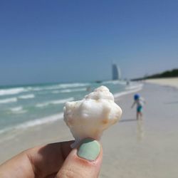 Close-up of hand holding ice cream against sea