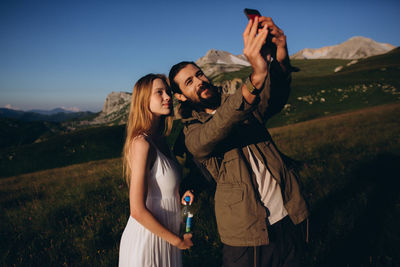 Young woman using smart phone while standing on mountain