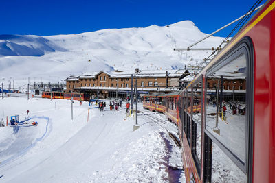 Train on snow covered field by alps against clear sky