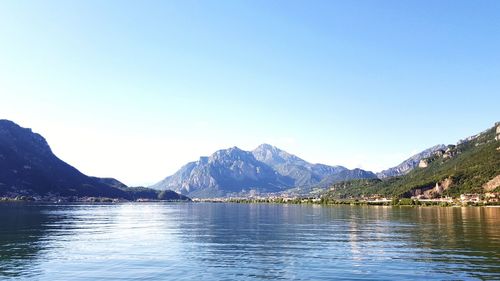 Scenic view of lake and mountains against clear blue sky