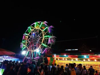 Low angle view of illuminated ferris wheel against sky at night